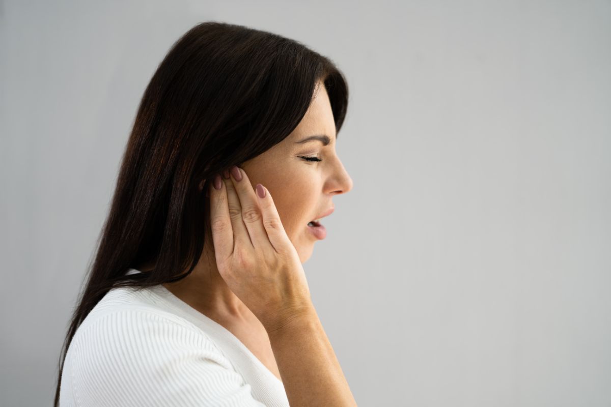 The woman is uncomfortable with her ear and wants to pop it.