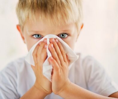Young boy blowing his nose into a tissue, illustrating symptoms addressed by post nasal drip child treatment.