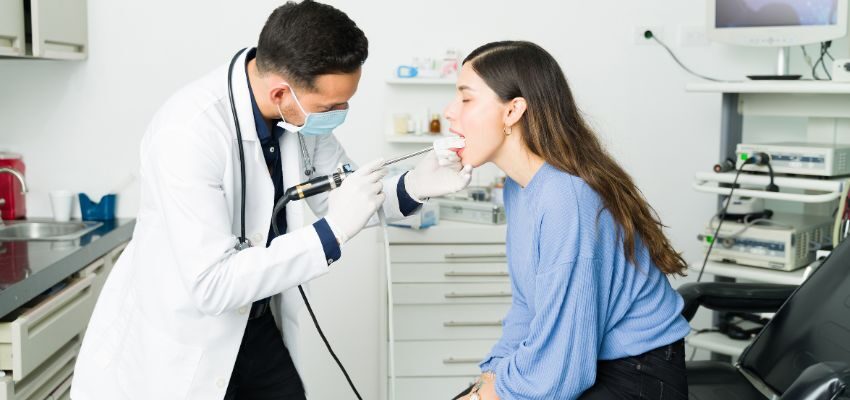 The doctor checks the woman to see if she has strep throat.