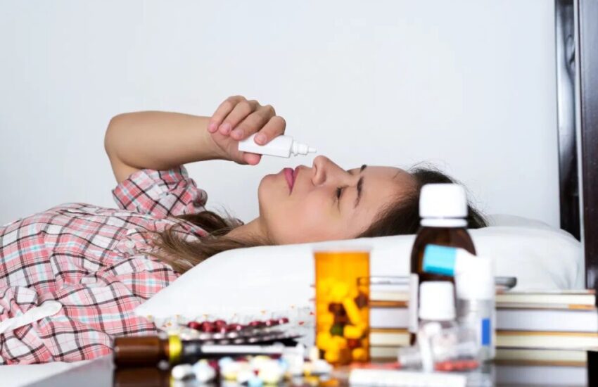 A woman lying in bed while inhaling a decongestant.