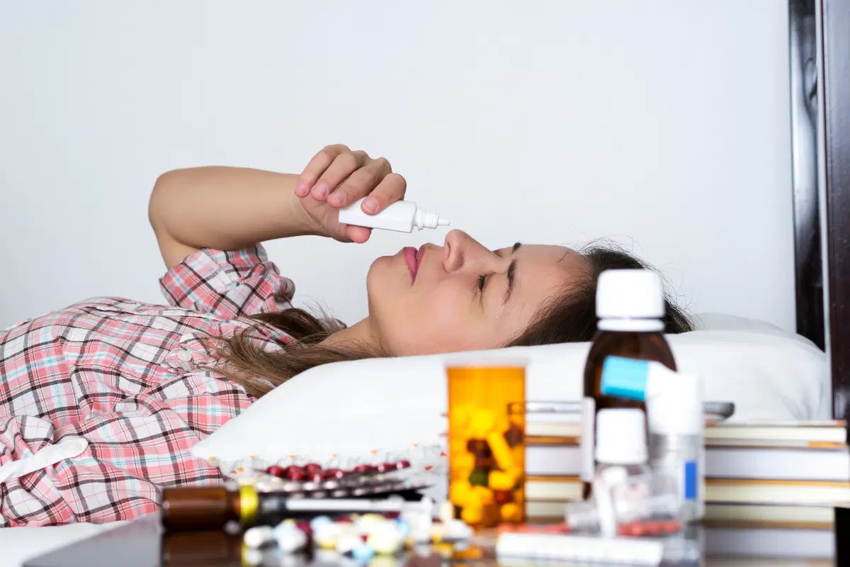 decongestant-versus-antihistamine A woman lying in bed while inhaling a decongestant.