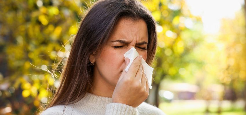 Woman blowing her nose outdoors after the sensation that her nose feels like inhaled water.