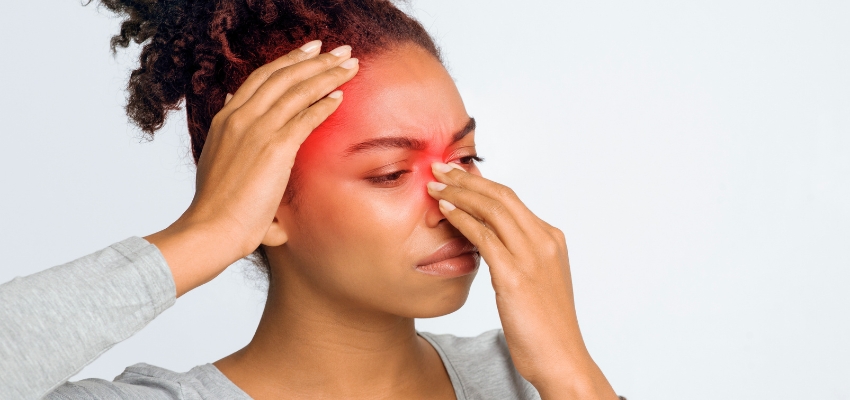 Woman pressing her forehead and nose in pain, a common reason to consider prednisone for sinus infection.