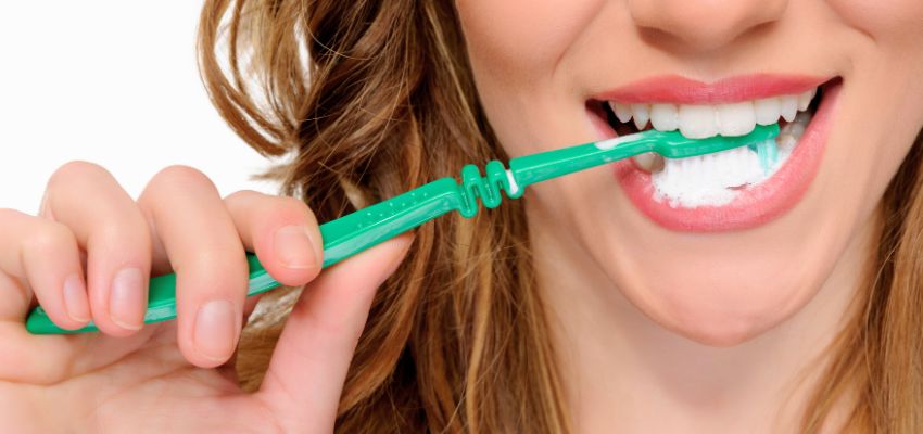 Close-up of a woman brushing her teeth but still experiencing breath that smells after brushing.