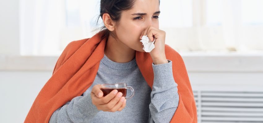 The woman drinks tea to relieve the flu.