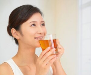 The woman drinks tea to relieve a sore throat.