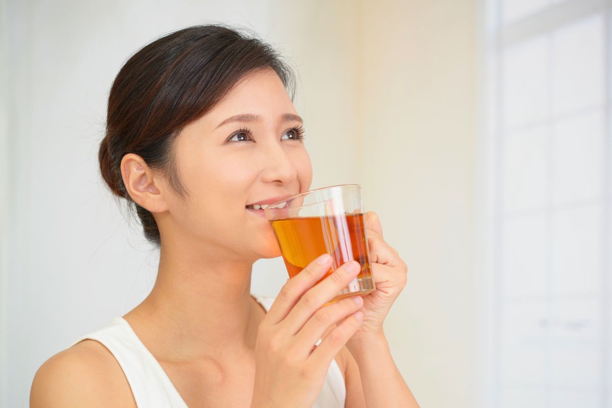 The woman drinks tea to relieve a sore throat.