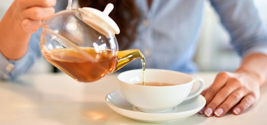 The woman poured tea into a cup.