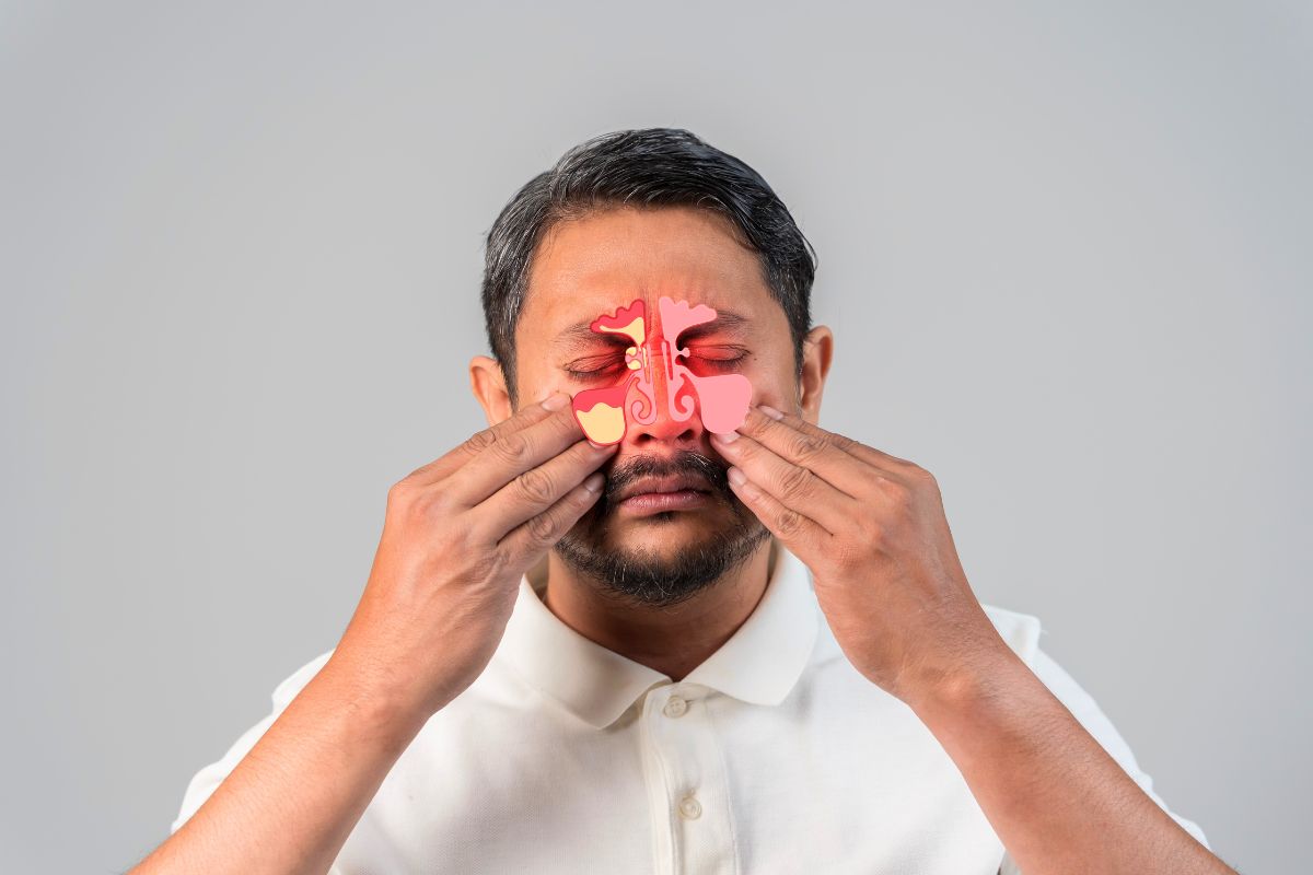 Sinuses burning: man pressing fingers on sinus points around nose and eyes with illustrated inflamed sinus overlay showing intense pressure and pain.