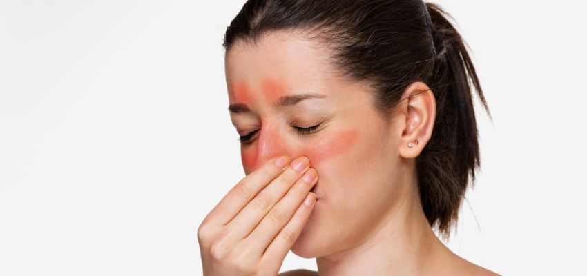 Sinuses burning: close-up of woman with visible red inflamed sinuses pinching bridge of nose in discomfort from severe sinus burning sensation