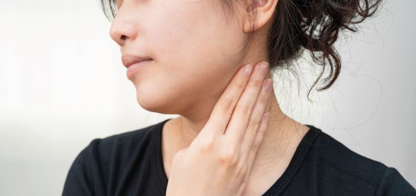 The woman holds her throat while she swallows.