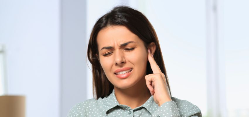 The woman is uncomfortable and has hearing problems due to Acute otitis media.