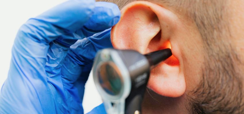 The doctor examines the man's ear to see if he has acute otitis media.