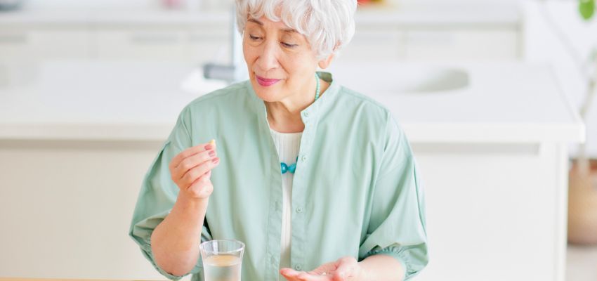 The older woman is taking probiotics to relieve viral pharyngitis.