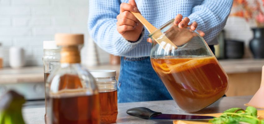 Is kombucha good for gut health depicted during kombucha brewing with a large glass jar and SCOBY