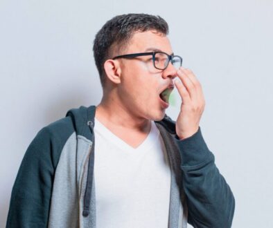 The man checks to see if his breath smells bad.