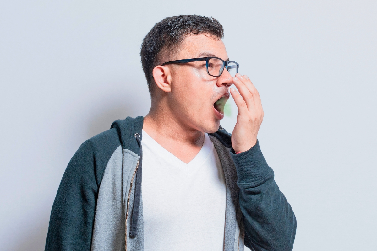 The man checks to see if his breath smells bad.