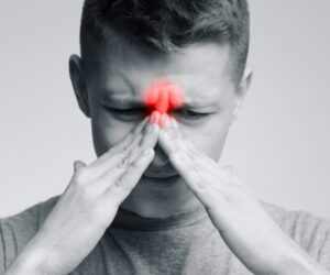 Man pressing his face in sinus pain, highlighting the need for foods that clear sinus congestion.