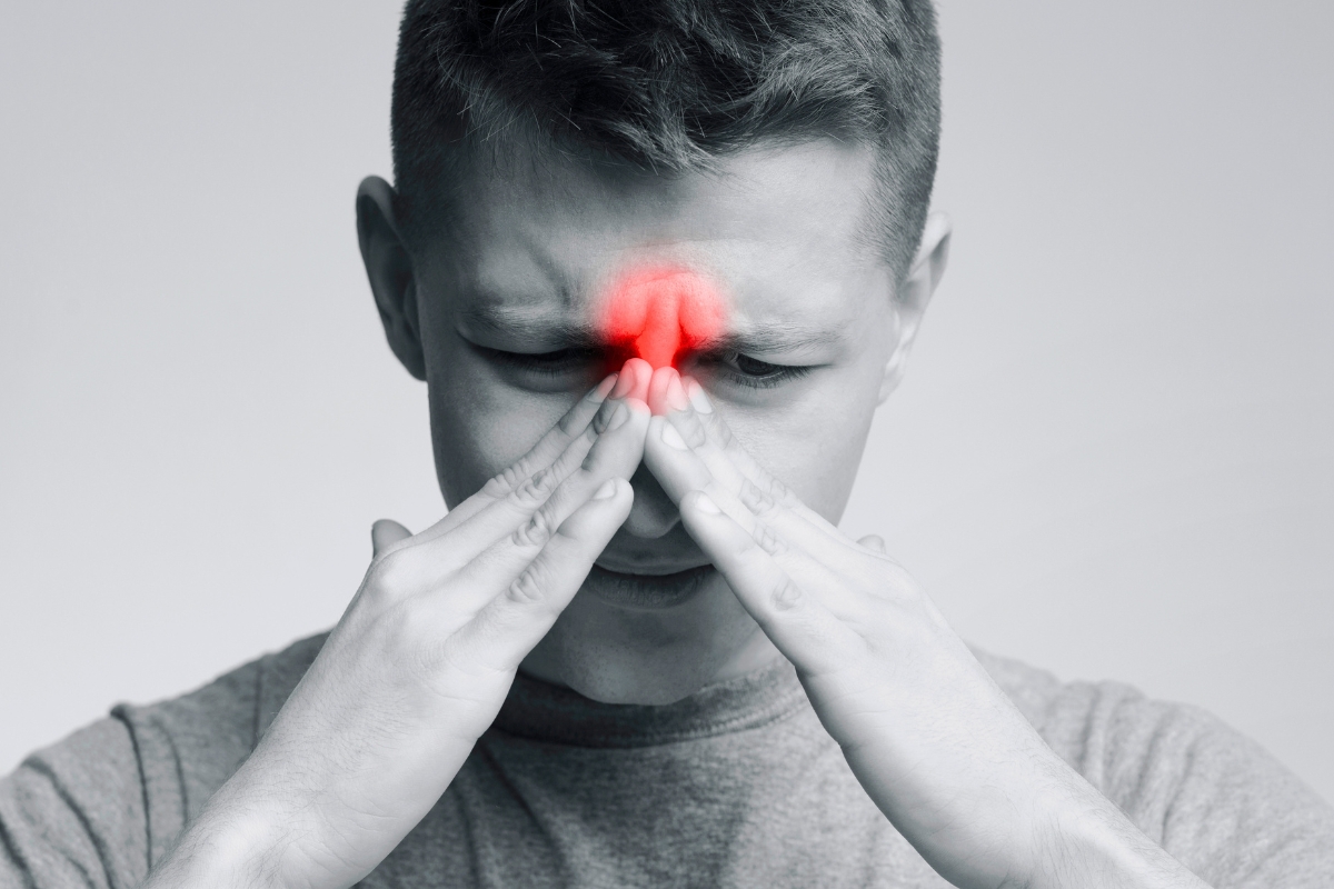 Man pressing his face in sinus pain, highlighting the need for foods that clear sinus congestion.