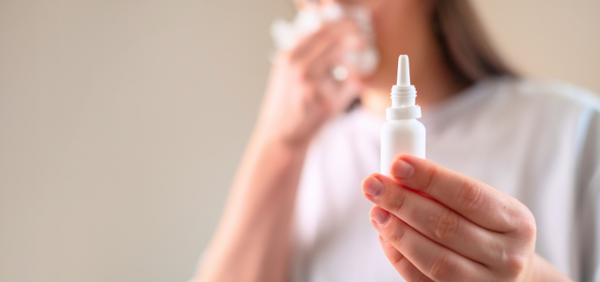 Hand holding nasal spray as a remedy for nasal congestion at night.