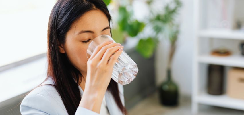 Woman drinking water for natural sinus pain relief and better hydration.