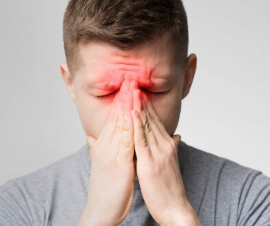 Man holding his face in discomfort, seeking sinus pain relief for pressure and headaches.
