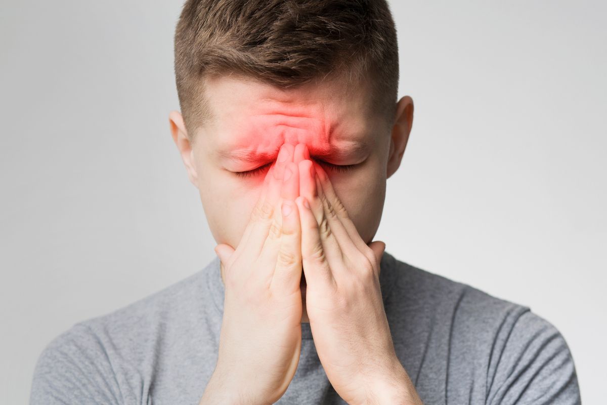 Man holding his face in discomfort, seeking sinus pain relief for pressure and headaches.