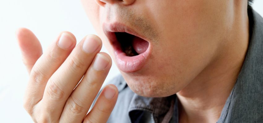 Man checking his breath to understand what does gingivitis smell like.