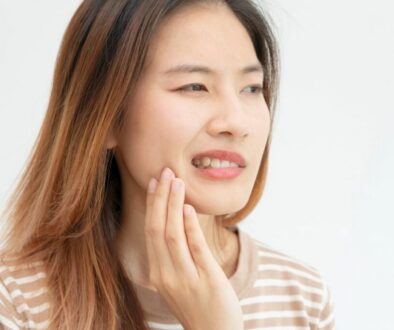 Woman holding her jaw in discomfort while noticing what does gingivitis smell like.