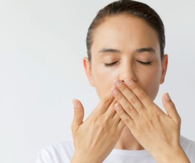 Woman covering her mouth while worried about bad breath after tooth extraction.